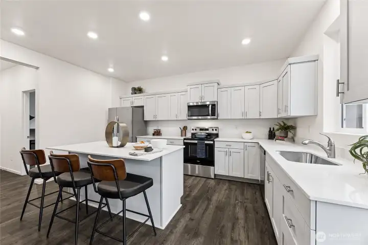 Modern kitchen with breakfast bar. hoto is representational. Actual home is under construction and colors, materials, and finishes may vary. See site agent for details.