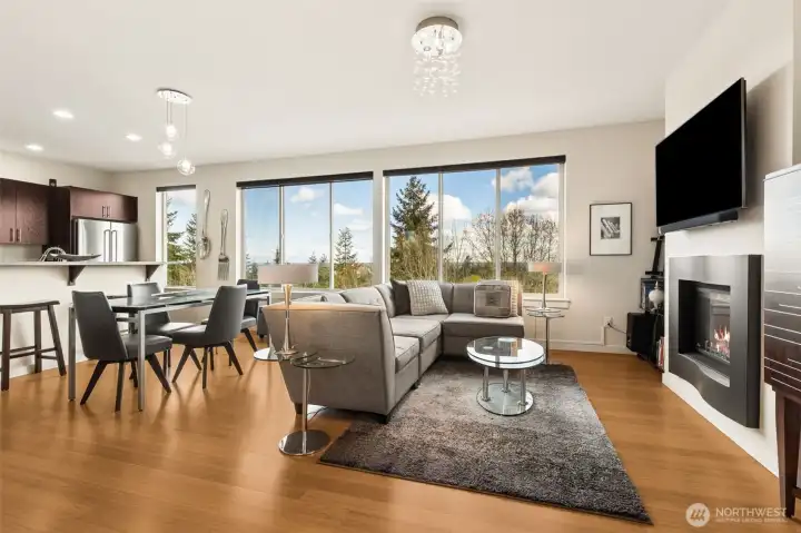 Main living space on the second floor is open and saturated with natural light, thanks to the wall of windows. Beautiful gas fireplace makes a statement and brings a cozy feel to the room.