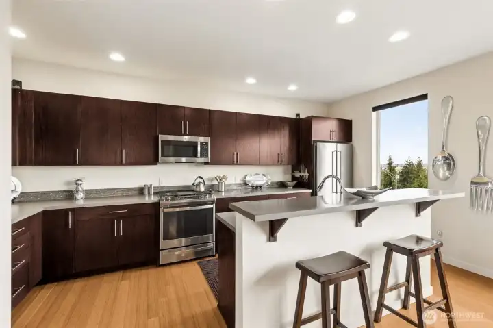 Kitchen has plenty of counter space for prep, and sleek stainless appliances. Eating bar provides more seating.