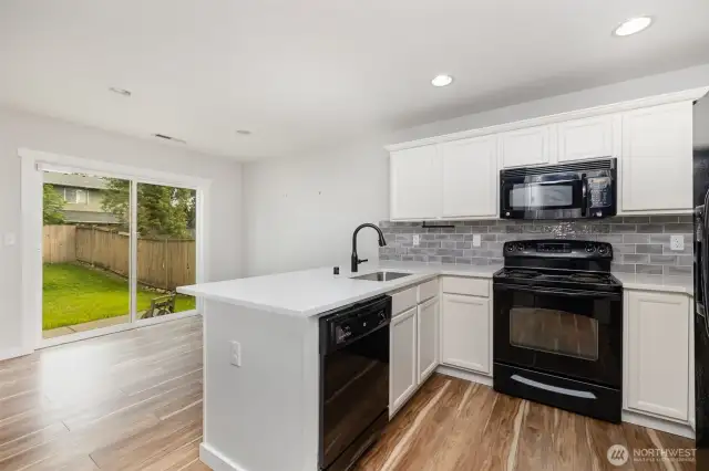 Beautifully updated modern kitchen featuring crisp white cabinetry, matching appliances, recessed lighting, and a thoughtfully designed peninsula for added functionality and style.