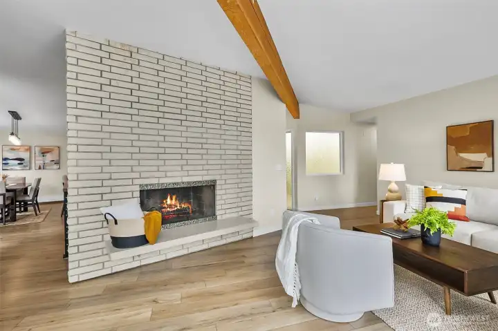 Mid Century Inspired Living Room Featuring Striking Floor To Ceiling Brick Fireplace With Wood Beam Accents.