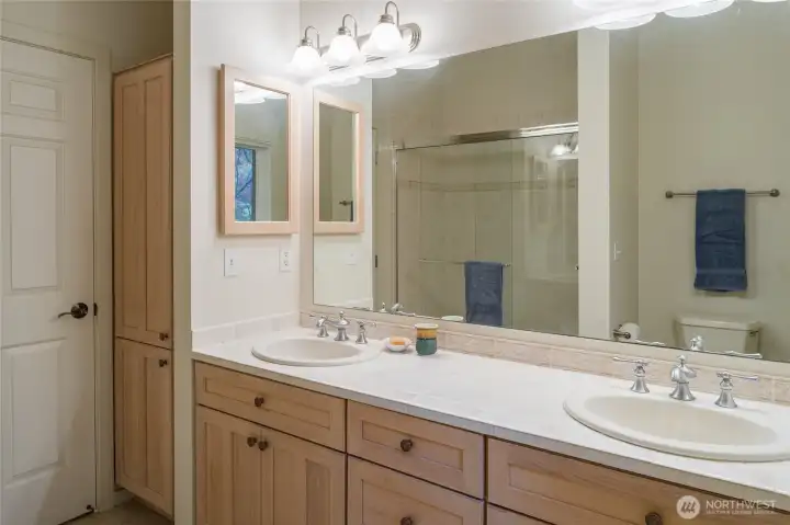 Primary bath has double sinks with tile counter.