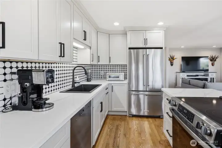 The kitchen features quartz countertops, new stainless-steel appliances, a new backsplash, and an oversized sink.