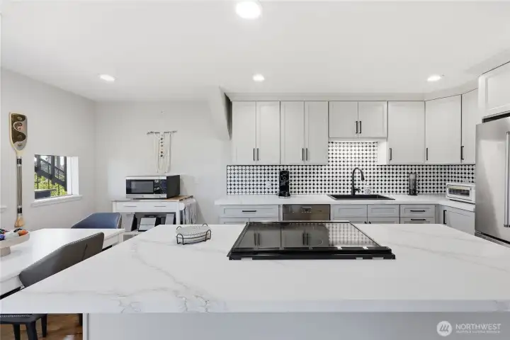The induction stove is complemented by an island that offers additional seating, ample storage, and ample space for entertaining.