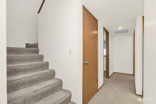 Stairs to 2nd level and 1st floor hallway to den/office and half bath with laundry.