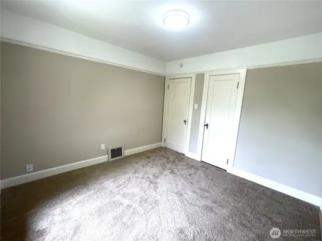 Here is the primary bedroom entry door and closet door and the furnace vent. New carpet, trim, lighting and paint.