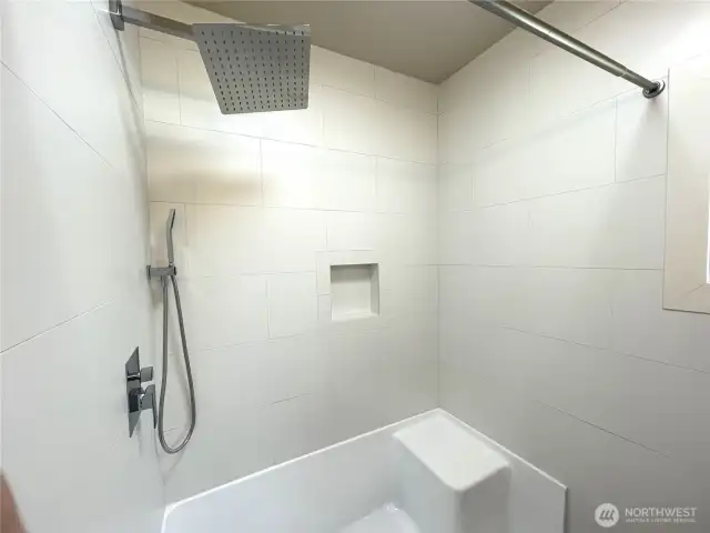 A beautiful white porcelain tiled shower enclossure. Featuers a seating area and a built in shampoo shelf. All new fixtures.