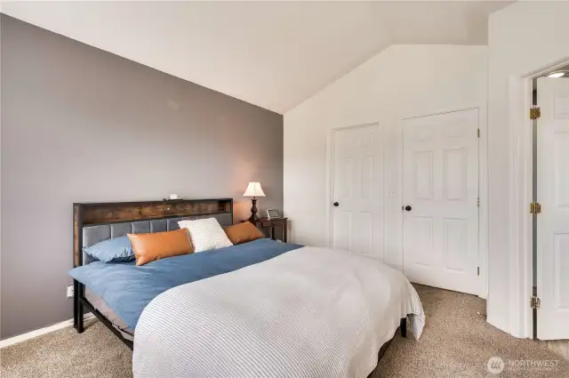 Primary bedroom with vaulted ceilings, doors to closet, hall and bath