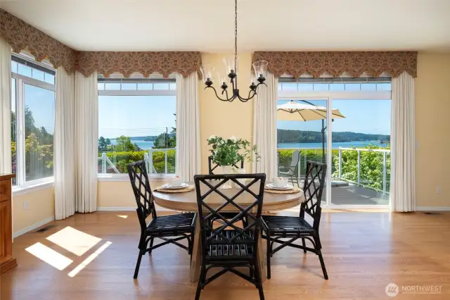 Large dining room with walls of windows drawing in the view.