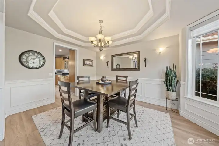 Elegant formal dining room with wainscotting, Coffered ceiligns and large windows.
