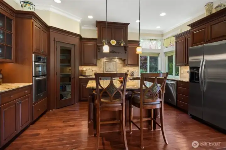 Crowd sized kitchen with eating island and cabinets to store kitchen ware for all occassions.