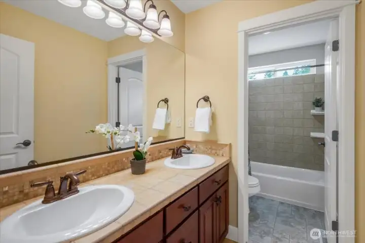 Auxiliary bath has double sinks and separate comode and bath area.