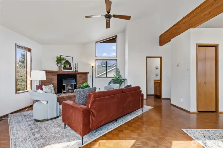 Living room with vaulted ceilings, exposed beam, and brick fireplace.