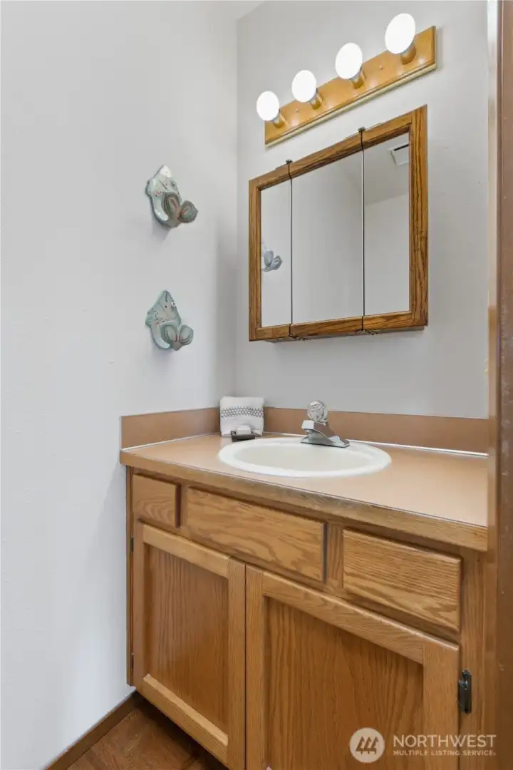 Convenient main-level powder room with single-sink vanity and wood cabinetry.