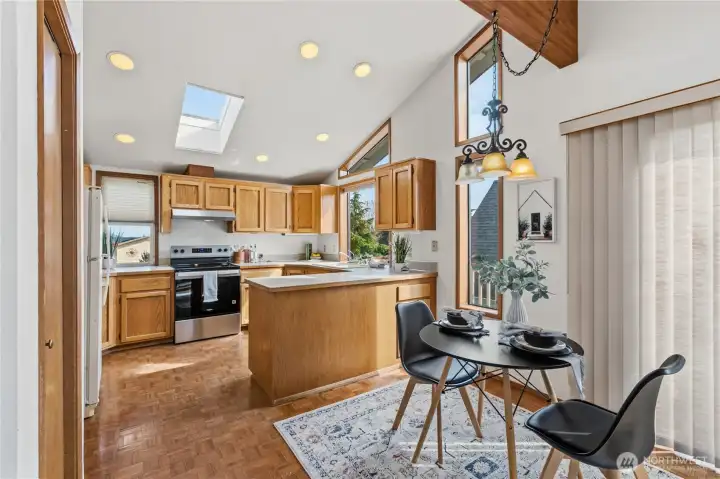 Kitchen with wood cabinetry, skylight, and adjacent dining area, designed for everyday functionality and natural light.