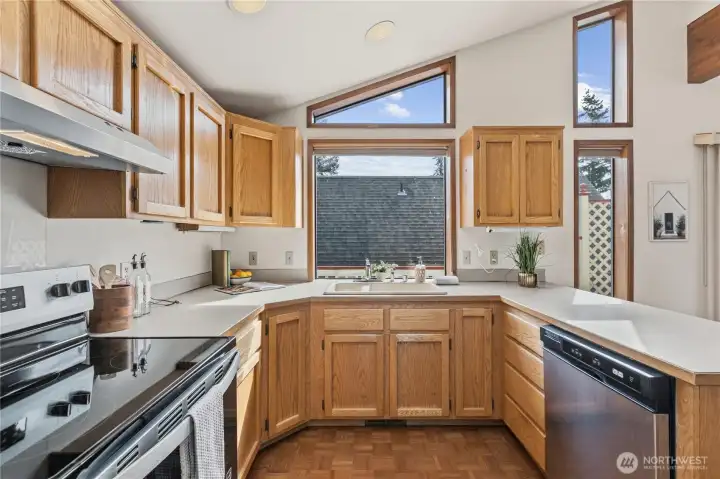 Open kitchen and living area with vaulted ceilings and expansive windows, allowing for a connected layout and abundant natural light.