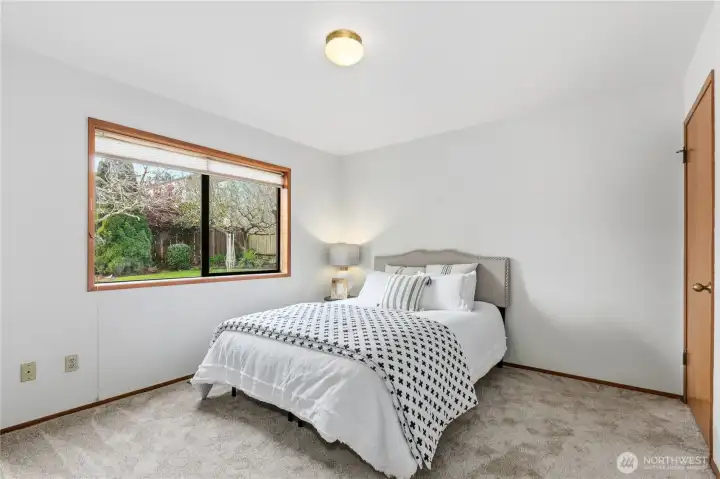 Primary bedroom with new carpet, fresh paint and large window overlooking the yard, allowing for natural light and a bright interior.