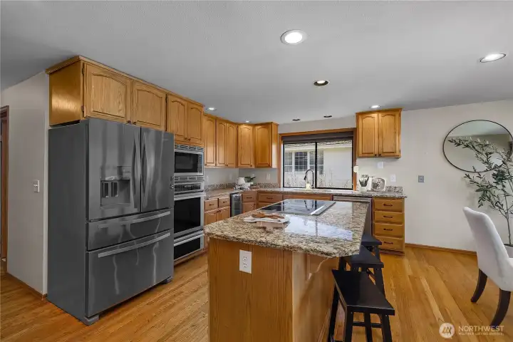 Spacious Stone and Stainless Island kitchen with abundant cabinetry, prep space, and everyday functionality.