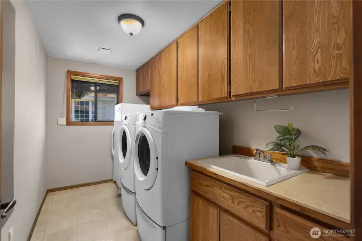 Spacious laundry room offers storage, utility sink, and everyday convenience.