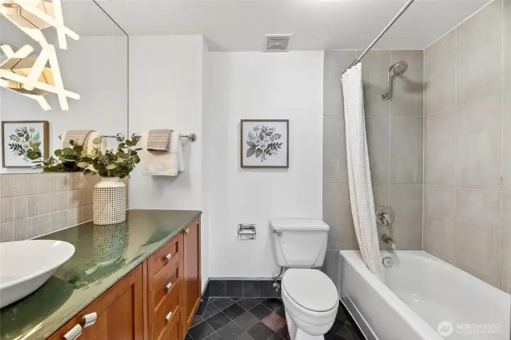 Designer lighting ceiling to cabinet mirror, custom tiling, glass counters and soaking tub complete the primary bathroom.