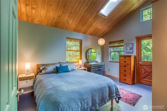 A vaulted tongue and groove wood ceiling contains a skylight streaming with morning light. The bedroom has an additional exterior entrance to a east stairwell.