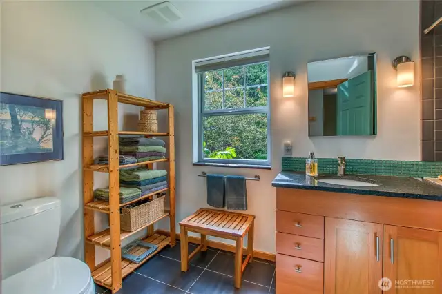 The full bathroom is spacious with porcelain tile flooring and beautiful wood cabinetry.