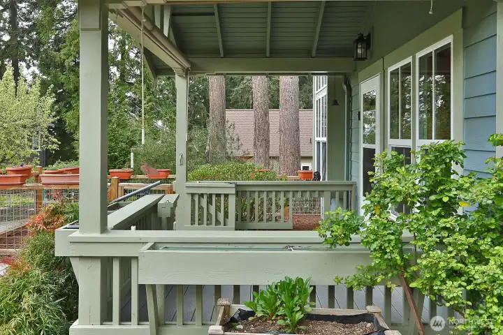 Covered back porch off the dining area with planter boxes is a great spot to sit outdoors and enjoy the fresh air and community lawn.