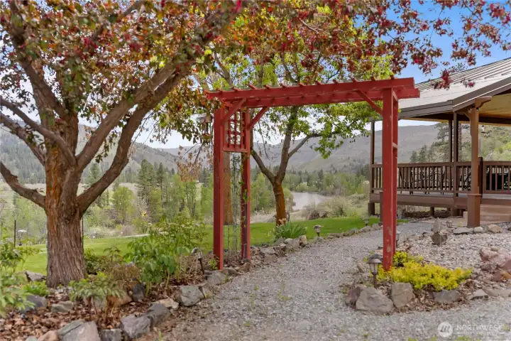 Charming garden entry with pergola and mature trees, leading to a peaceful outdoor setting with beautiful river and mountain views beyond.  Only minutes to the Carlton Swimming hole.