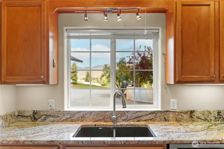 Kitchen sink window with granite counters and pleasant views, bringing natural light into the space