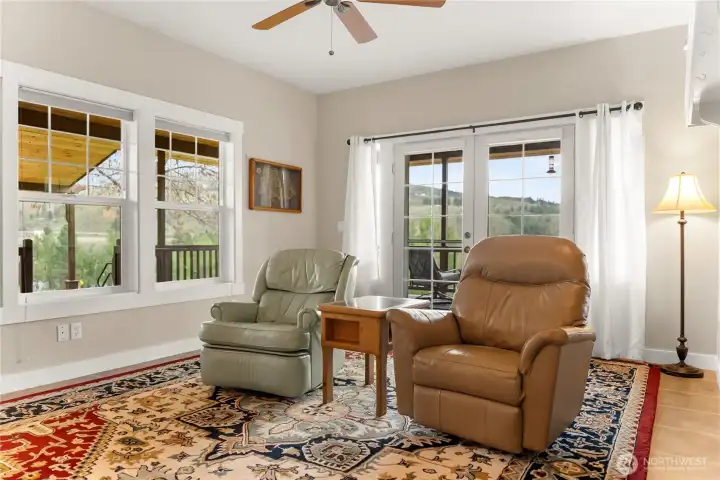 Bright, open living room wrapped in windows, seamlessly extending to the covered porch for effortless indoor-outdoor living and year-round enjoyment