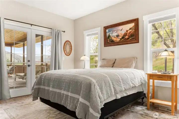 Light-filled primary bedroom with French doors opening to the deck, complemented by a spacious walk-in closet and a peaceful, airy feel.