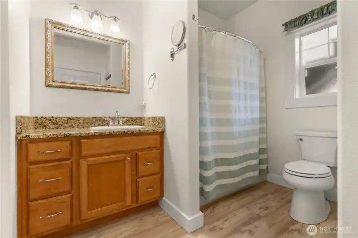 Large bright full bath featuring warm wood cabinetry, generous counter space, —designed for comfort and everyday ease.