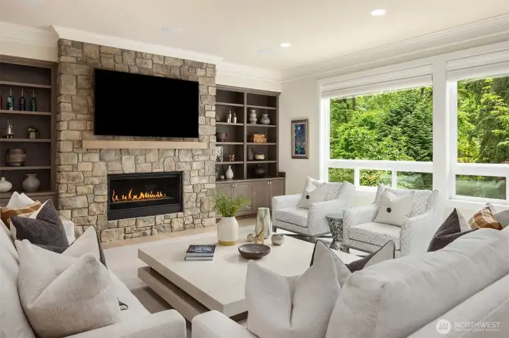The great room features a stone surround gas fireplace flanked by custom cabinets.