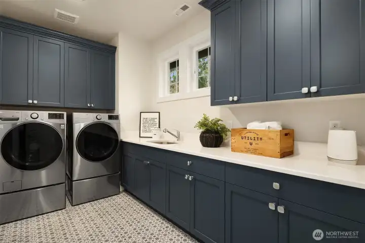 Upper level laundry room with ample built-in cabinetry & undermount sink.