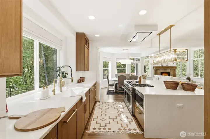 The showpiece kitchen is anchored by a waterfall quartz island, custom white oak cabinetry, and a curated suite of professional-grade appliances, including Thermador full-size refrigerator and freezer columns, dual Thermador Emerald dishwashers, a Sub-Zero beverage refrigerator, Miele built-in coffee system, Wolf microwave, and an oversized wine storage unit.