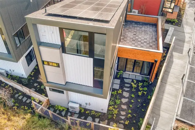 The aerial view showcases the home's impressive solar panels, expansive backyard, and inviting roof deck. These features highlight the property's commitment to sustainability and outdoor living.