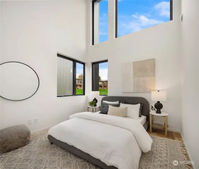 The second primary bedroom features soaring ceilings, large windows, and direct access to the full bath upstairs, creating a spacious and inviting retreat.