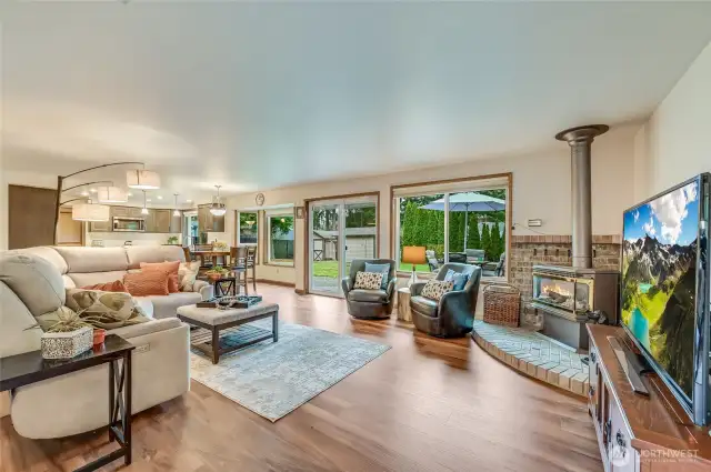 view of family room adjoins kitchen, toasty fireplace & tons of windows