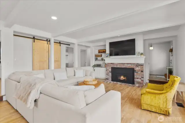 Sunken living room with hardwood floors, brick fireplace and built-ins.