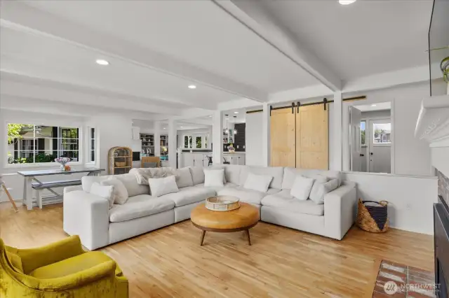 Open concept sunken living room with hardwood floors, ceiling beam detail and recessed lighting.