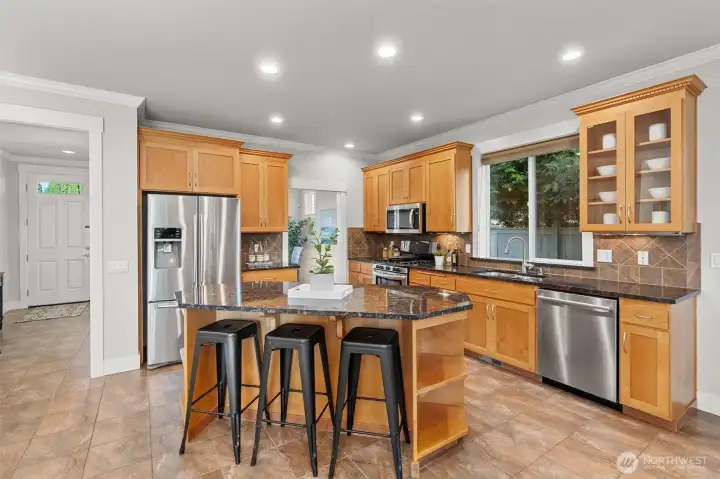 Kitchen with granite counters, tile floors & backsplash, stainless appliances & pantry.