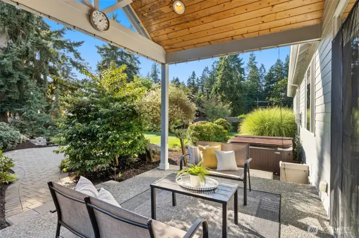 Fully fenced backyard retreat with custom waterfall, covered patio with hot tub, irrigation system, landscape lighting, raspberry & rhubarb plants, and storage shed.