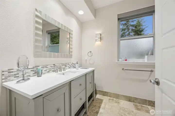 Bathroom with quartz countertop and tile backsplash.