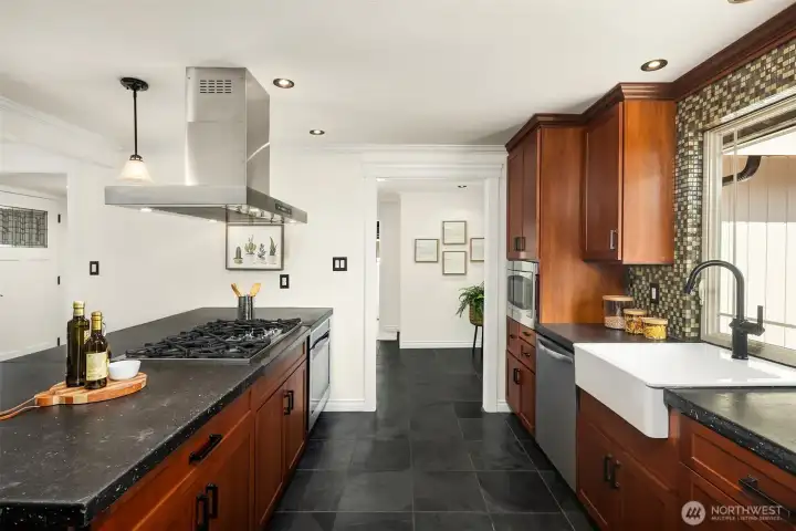 Large farmhouse style kitchen sink overlooks the yard. Tiled flooring continues throughout kitchen, dining and hallway for continuity and easy cleaning!
