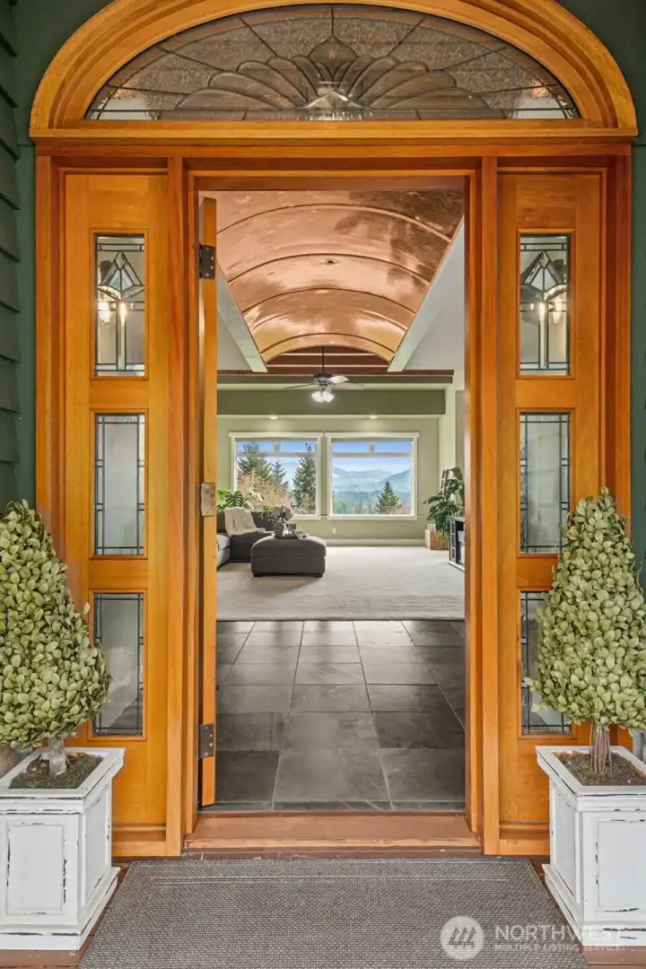 The large, covered entry has a Honduran Mahogany door with custom matching transom and clear, stained glass sidelights. Beautiful El Dorado stone accents. It sets the tone for the entire home, blending artistry and function in a way that feels both timeless and distinctly Pacific Northwest.