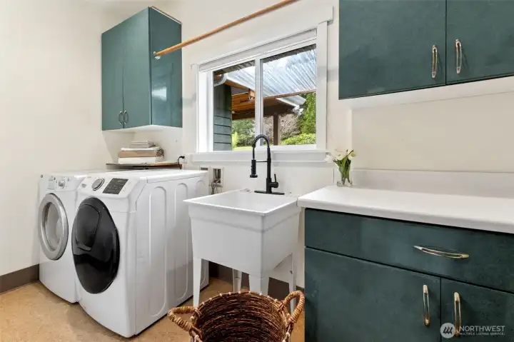 Spacious Main floor laundry with utility sink and generous storage cabinetry/work space.