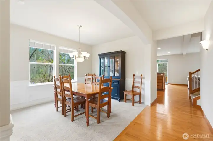 Dining room with wainscoting, high ceilings, and windows framing greenbelt views