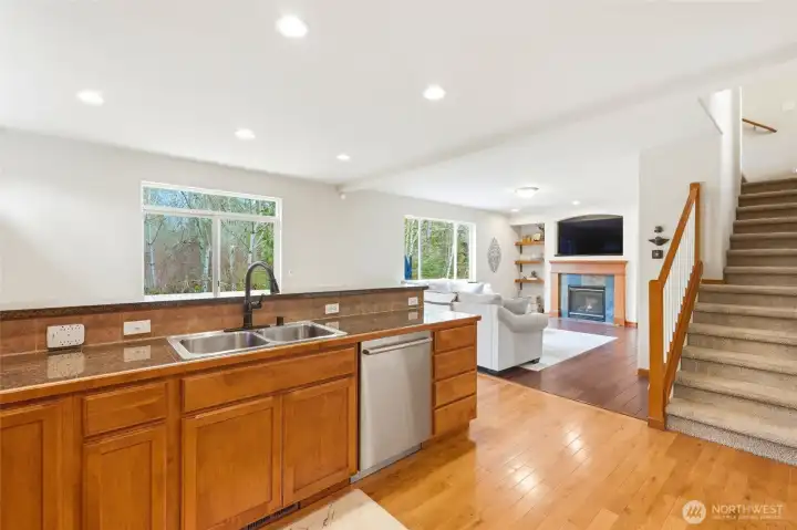 Kitchen eating bar opens to family room with gas fireplace and greenbelt views