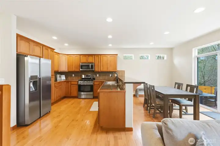 Open-concept kitchen and family room with hardwood floors and greenbelt views