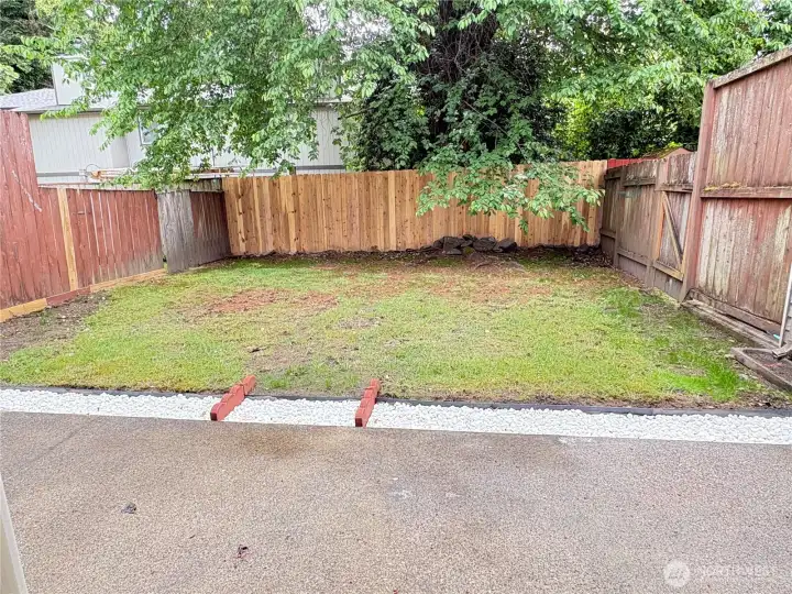 View from dining space and kitchen overlooking good sized yard with patio that runs entire width.